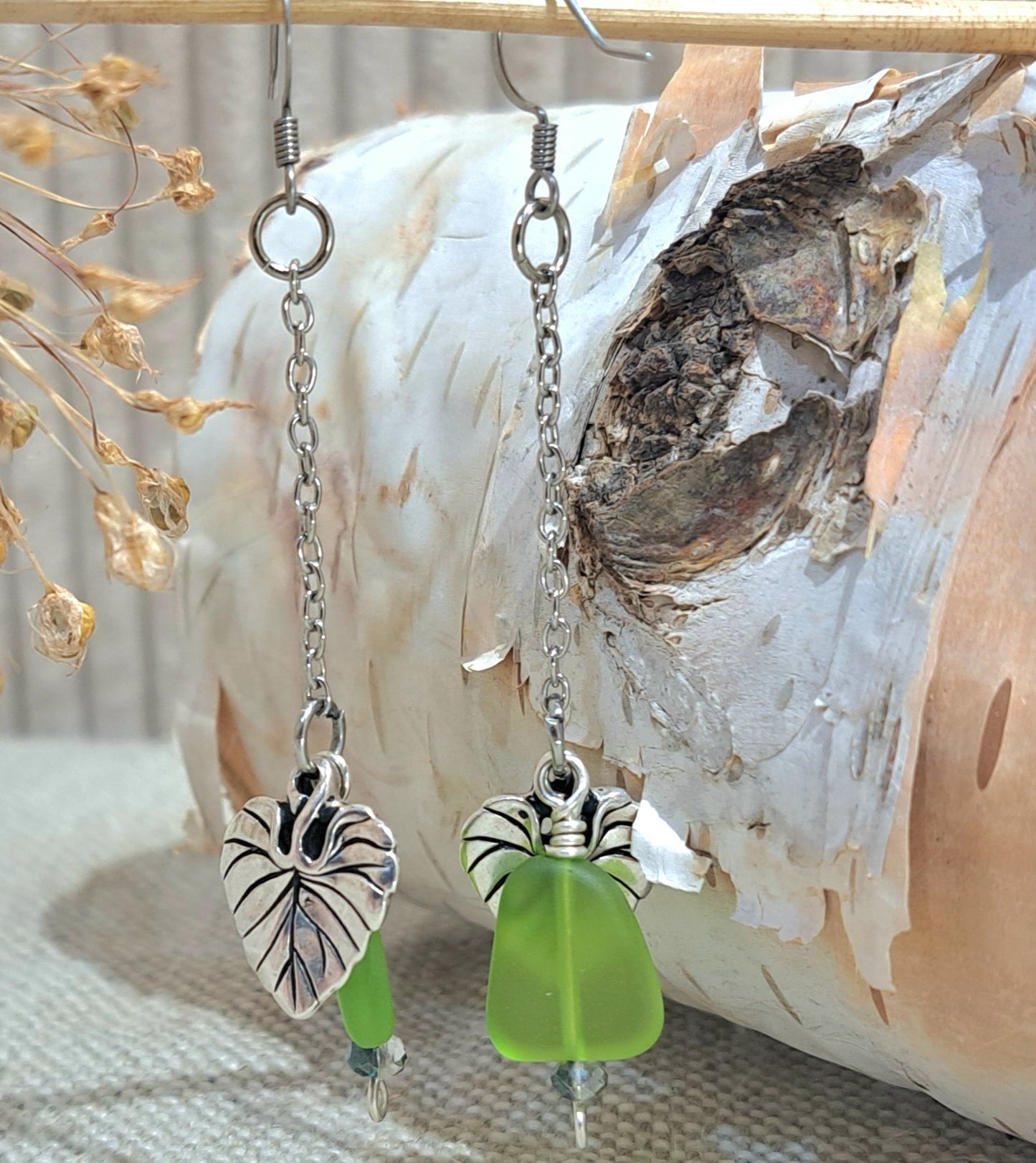 Stainless Steel dangle earrings with green glass and leaf charm.