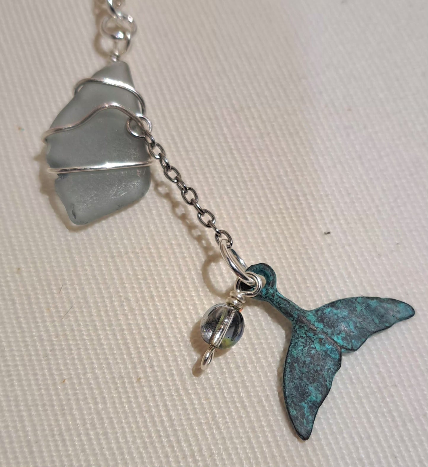 Whale tail charm, and wire wrapped grey sea glass necklace, on silver plated stainless steel chain.