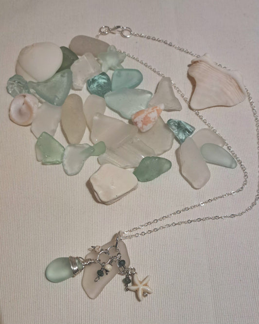 Sea glass clear and pale green with ivory star on silver chain.