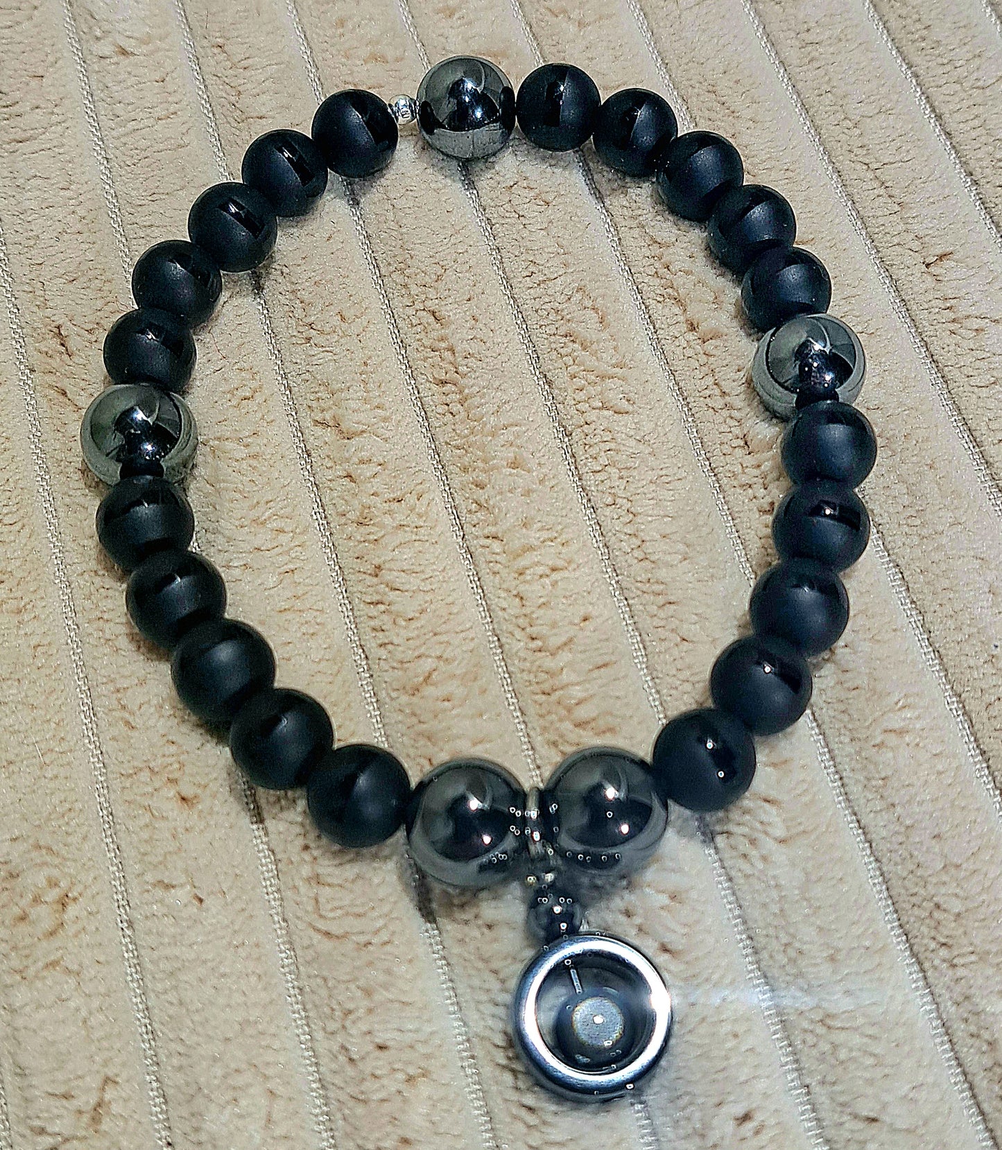 Unisex stretch bracelet of Black Onyx with polished stripe detail and Hematite Charm.