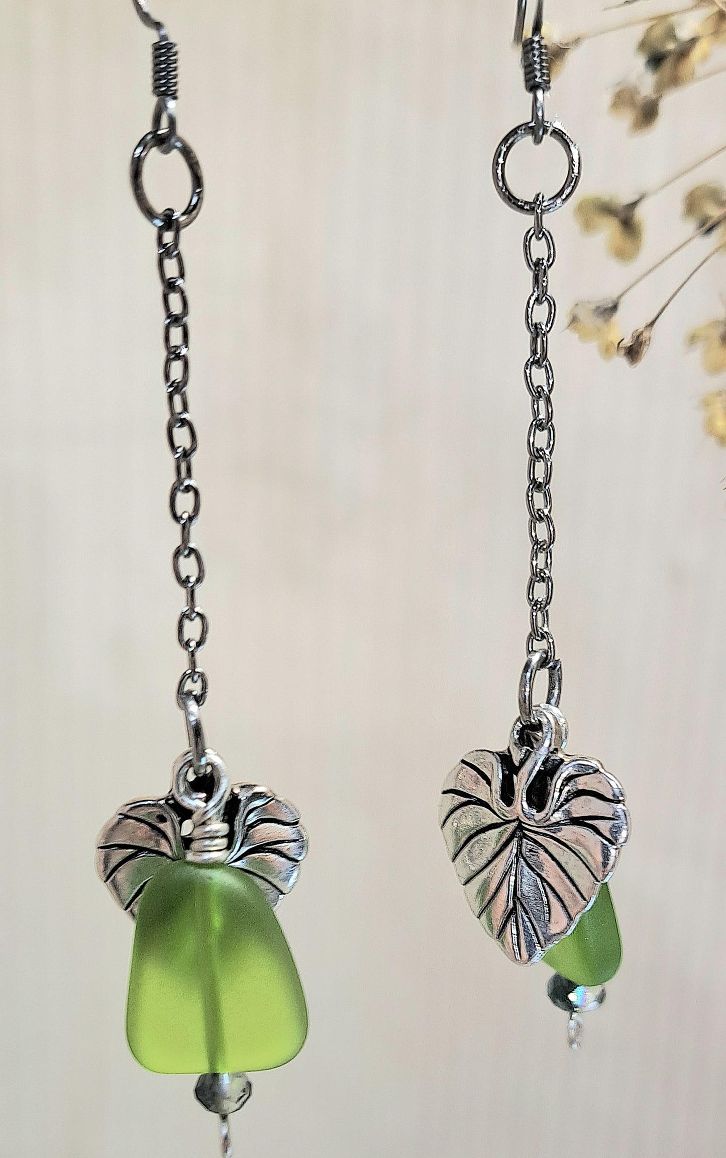Stainless Steel dangle earrings with green  glass and leaf charm.