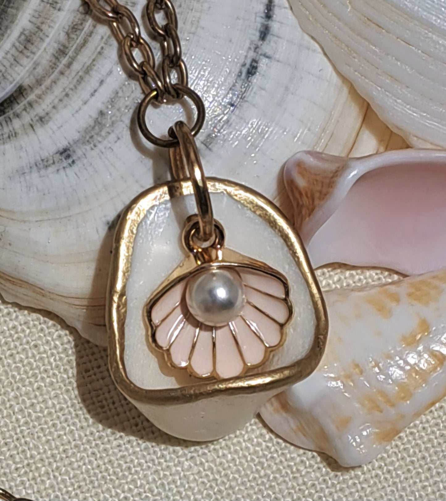 Cup shaped sea shell pendant with pink clam shell charm and hanging pearl.