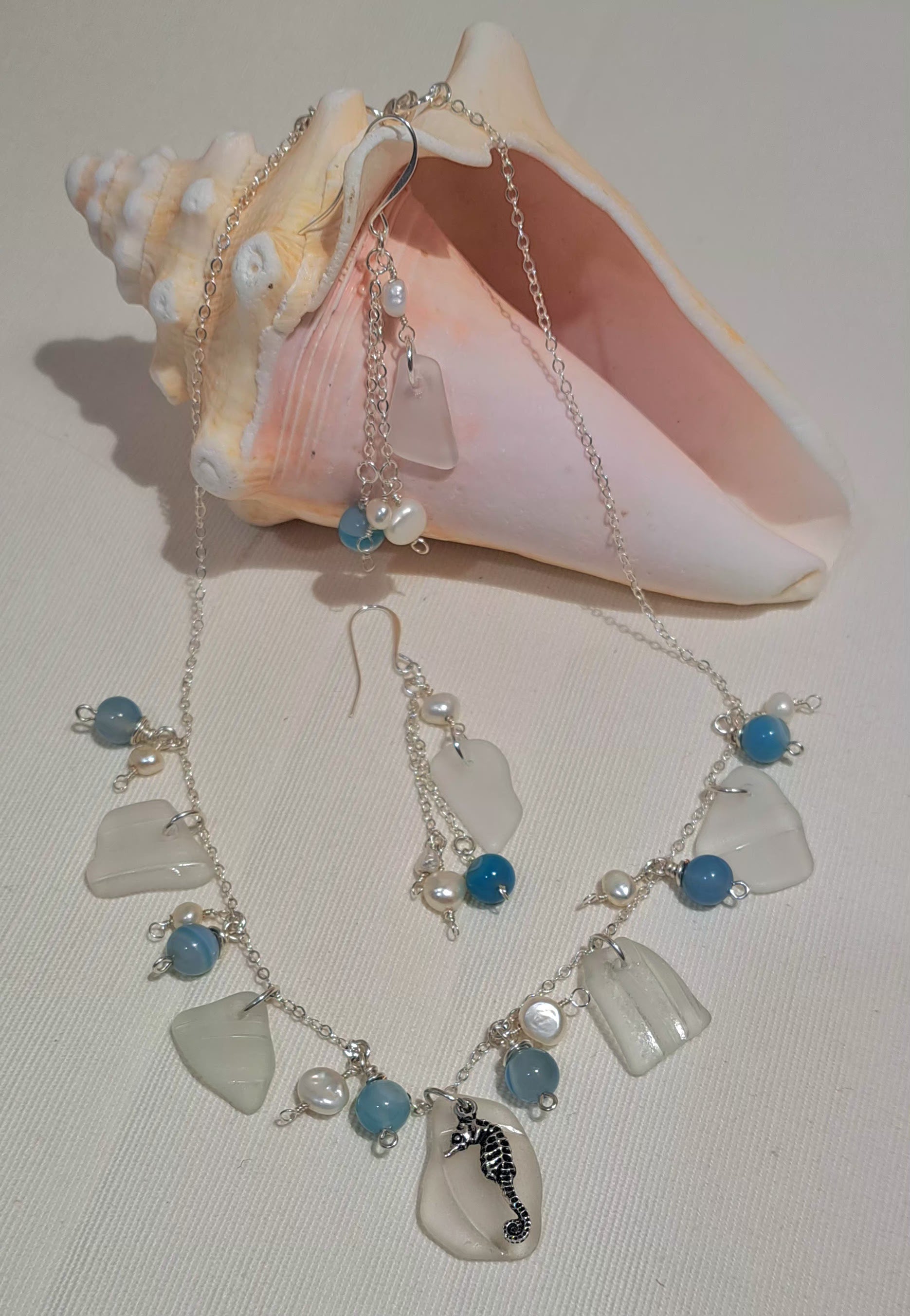 Necklace in silver featuring white sea class chips that all have a multi ridge texture and accented with turquoise beads and pearls between the glass