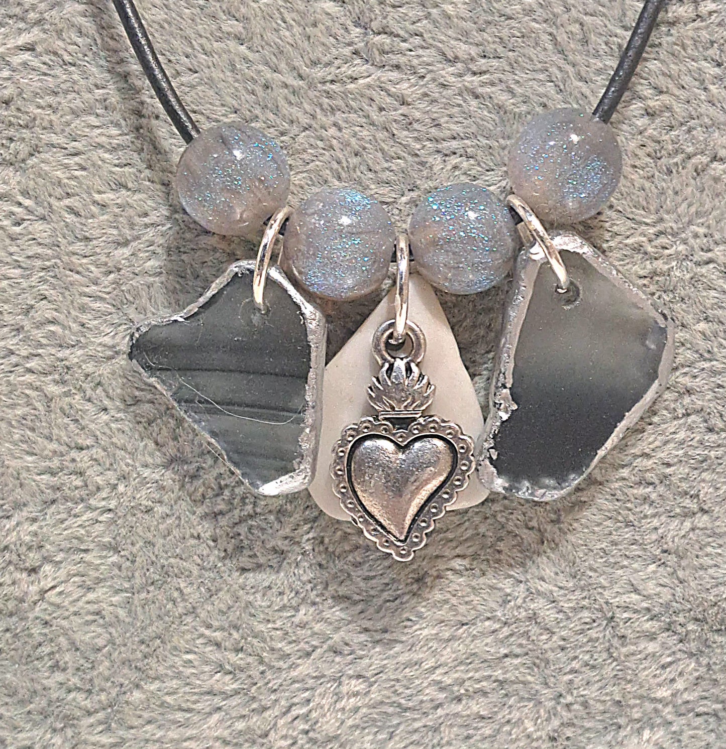 Close up of Ladies grey sea glass and resin beads on leather shows the sparkle of the resin beads and white tile chip and stainless steel heart charm.