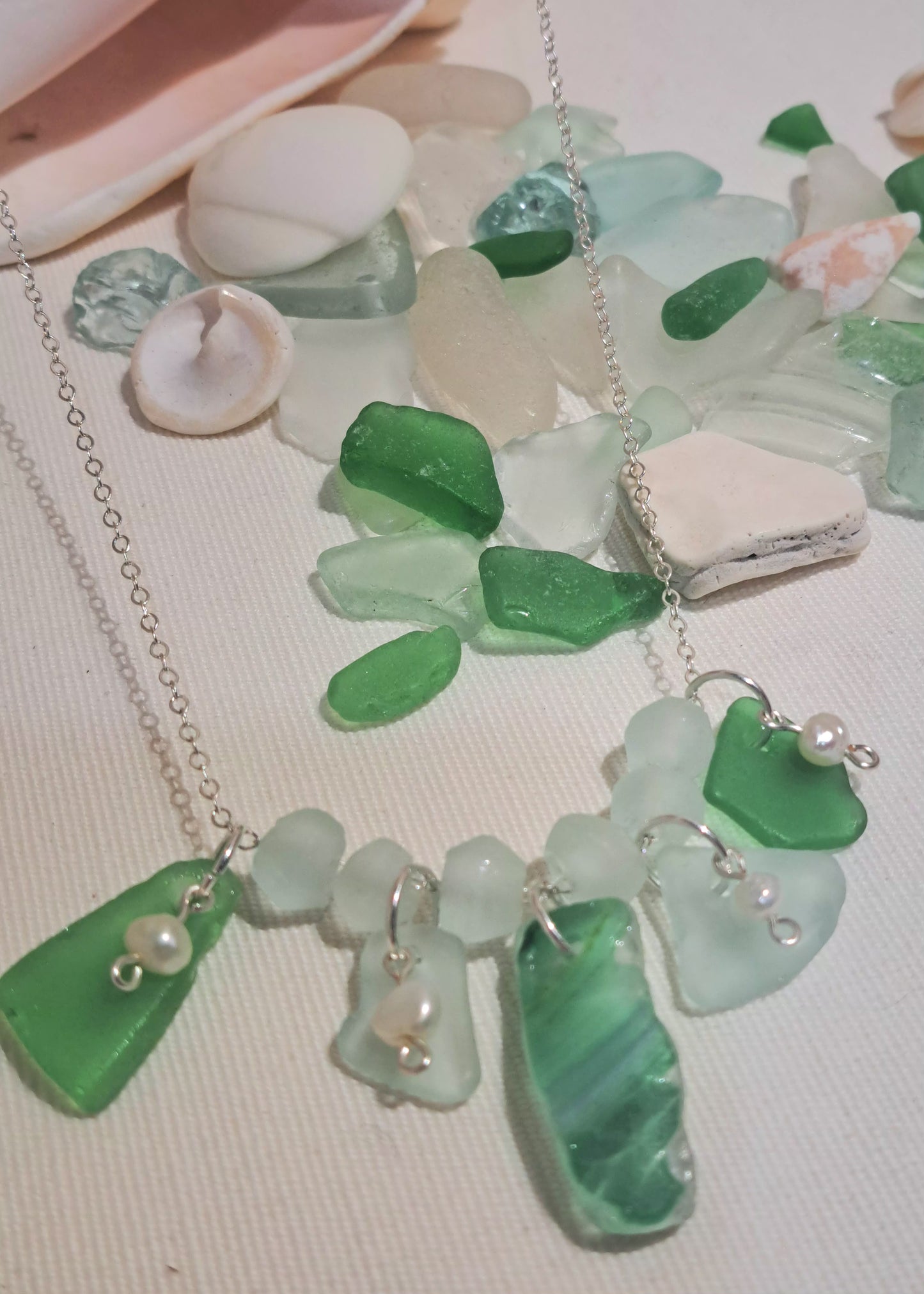Green and blue toned stripped sea glass chip hung on silver chain with two green solid sea glass chips and tiny fresh water pearls